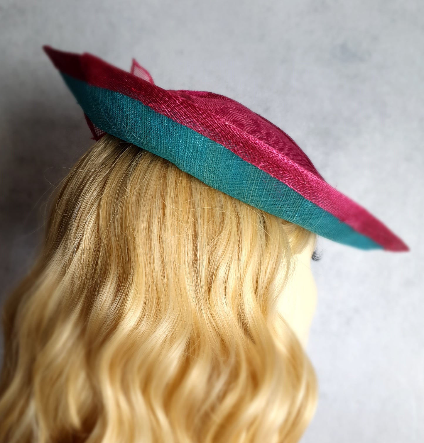 Elegant fascinator hat for women in fuchsia and blue. Handmade from sinamay with abaca silk, for weddings or formal events.