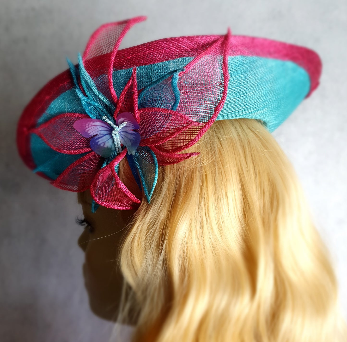 Elegante fascinator hoed voor dames in fuchsia en blauw. Handgemaakt van sinamay met abaca zijde, voor bruiloften of formele evenementen.