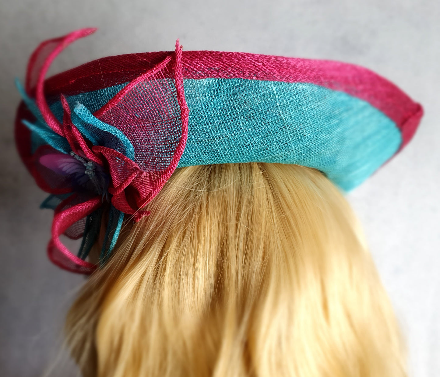 Elegant fascinator hat for women in fuchsia and blue. Handmade from sinamay with abaca silk, for weddings or formal events.