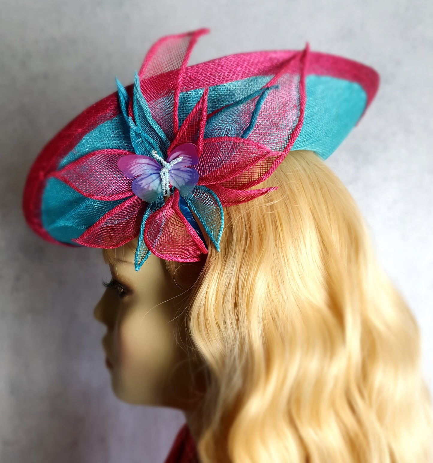 Elegante fascinator hoed voor dames in fuchsia en blauw. Handgemaakt van sinamay met abaca zijde, voor bruiloften of formele evenementen.