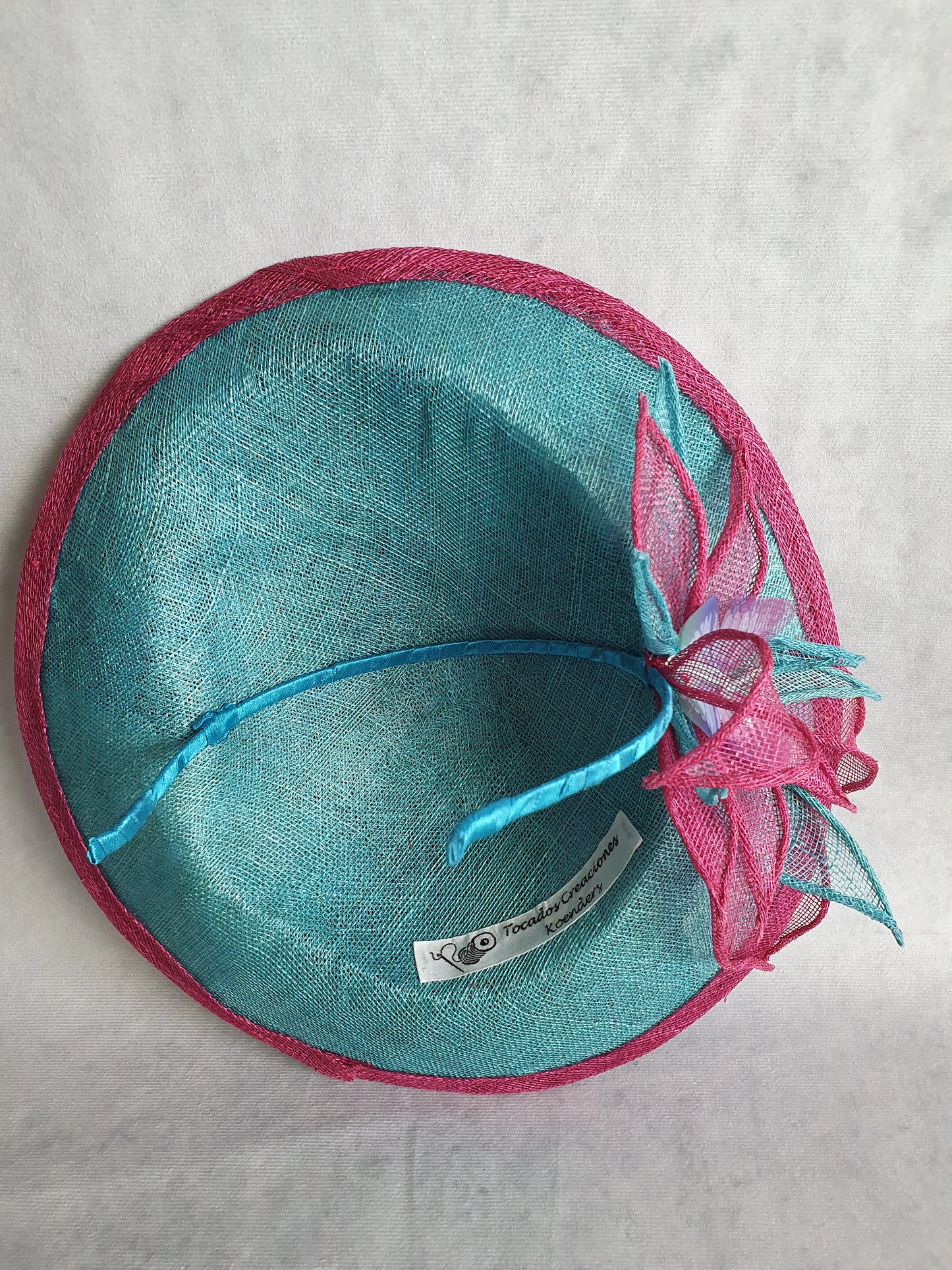 Elegante tocado para mujer en color fucsia y azul. Hecho a mano en sinamay con seda de abacá, para bodas o eventos formales.