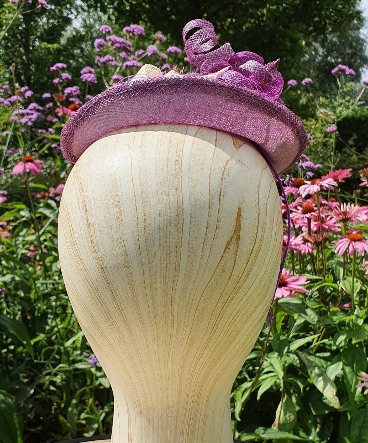Handgemaakte paarse ovale fascinator van sinamay met roze en paarse veren en striken